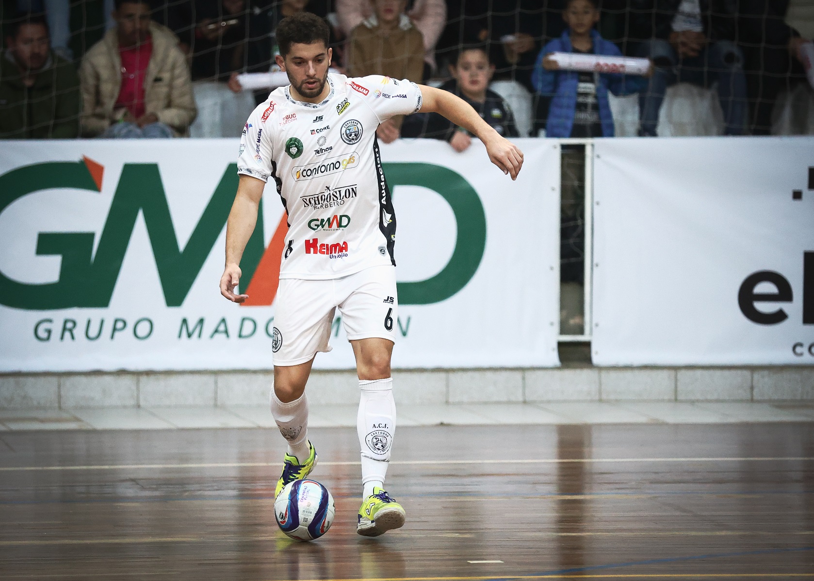 Jogador de futsal com uniforme branco em quadro ameaçando dar um passe